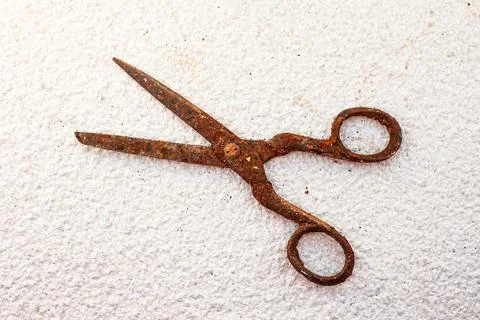 Old vintage scissors covered in rust on white stone background - isolated Stock Photos