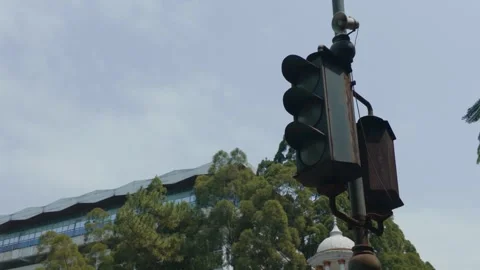 Old vintage traffic light hanging on a pole against cloudy sky and trees. Video stock 343371547