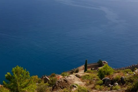 The old wall of the ancient castle is visible against the blue sea Stock Photos