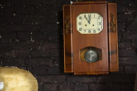 Old wall clock with a pendulum on a brown brick wall background Stock Photos