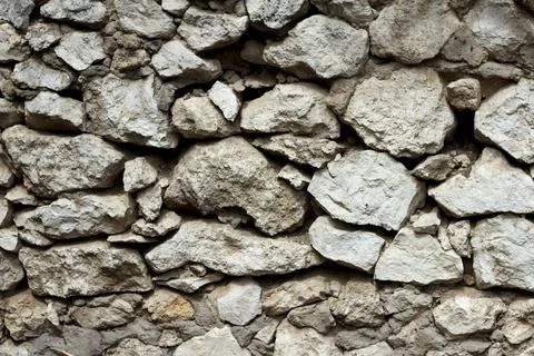Old wall of gray stone booth, cement sprinkled in places, needs repair Stock Photos