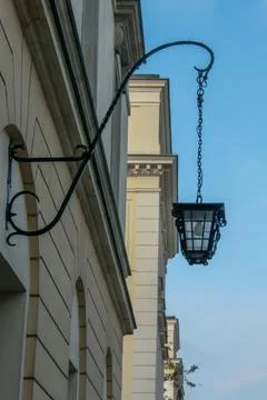 An old wall lantern made of oxidized forged steel located on the wall of one Stock Photos