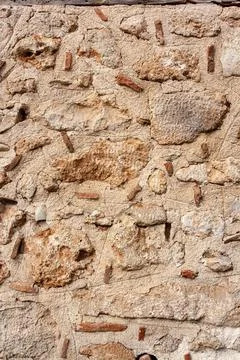 Old wall from large and small stones inside of cement mortar. Vertical photo. Stock Photos