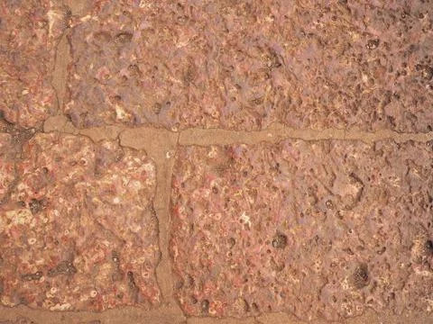 An old wall made up of blocks cut from red lava rock Stock Photos