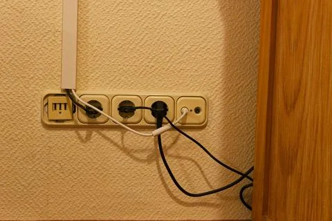 Old wall outlets and surface cables on a beige wall Stock Photos