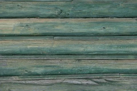 An old wall of pine logs. Weathered, faded wood. Green paint faded in the sun Stock Photos