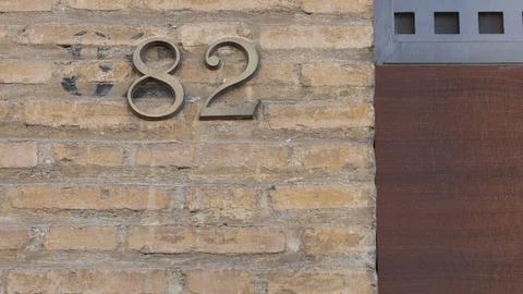 Old wall texture of rectangular mud bricks with the number 82 Stock Photos