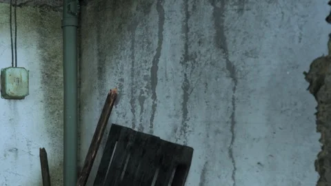 Old wall with water stains and wooden pallet in a dimly lit space Stock Footage 343946495