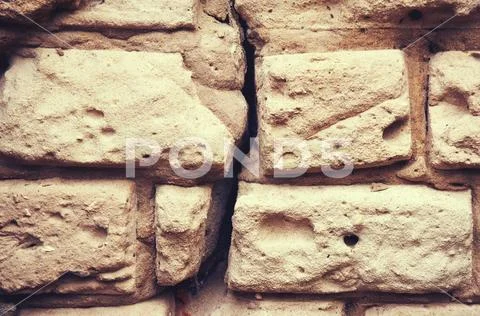 Old wall from a white brick shattered, cracked plaster. Abstract background. Stock Photos