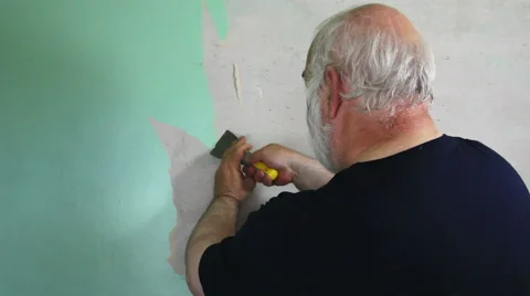 Old wallpaper stripping by man doing re-decorating DIY over the shoulder Stock Footage 55867777