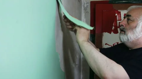 Old wallpaper stripping by man doing DIY re-decorating side view Stock Footage 55867879