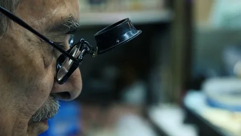 Old Watchmaker working in his shop. Lateral Close Up Stock Footage 73539226