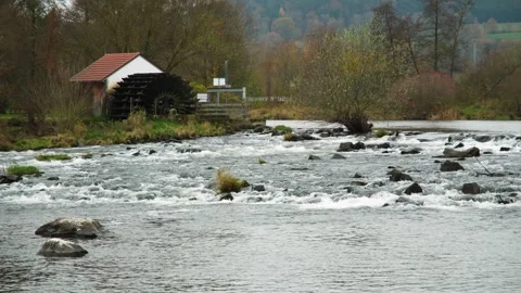 Old water mill with rotating wheel on a river, generating eco-friendly energy Stock Footage 292542707