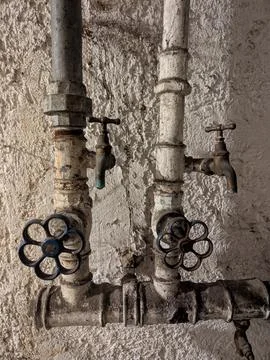 Old water taps attached to a wall in a rustic, aged outdoor setting with me.. Stock Photos