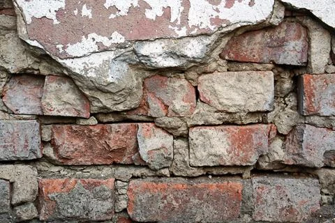 Old weathered brick wall with peeling plaster and crumbling cement texture Foto stock