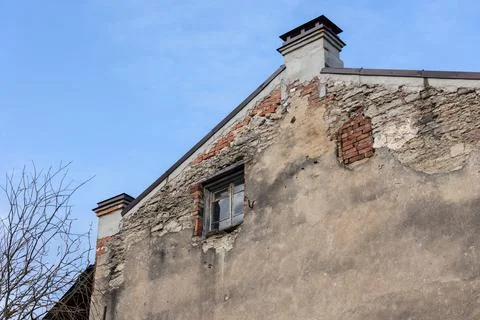 An old weathered building facade with cracked plaster, an aged broken window Stock Photos