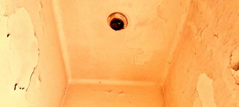 Old weathered ceiling with a single circular light fixture installed Stock Photos