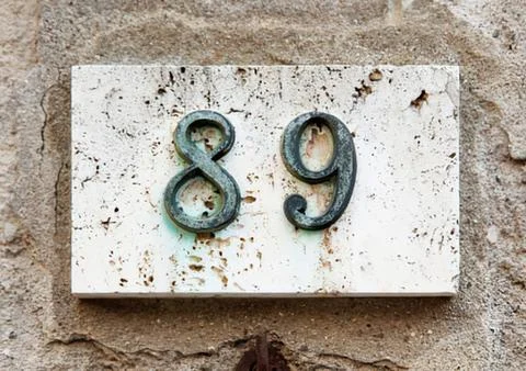 Old weathered concrete numbers eighty-nine sign Stock Photos