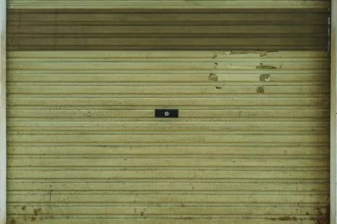 Old weathered metal rolling shutter door of a closed shop Foto stock