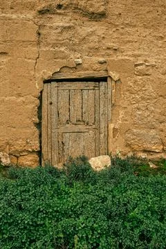 An old, weathered wooden door set in a rustic stone wall Stock Photos
