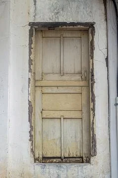 An old, weathered wooden window with peeling paint and cracks in the surrou.. Stock Photos