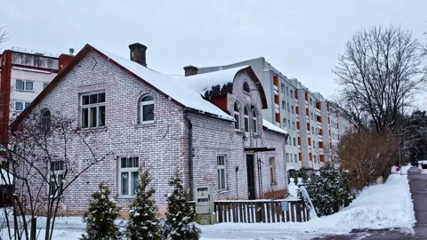 Old white brick house standing among post soviet residential buildings in Stock Footage 329004443