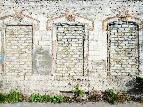 Old white brick wall with three bricked windows Stock Photos