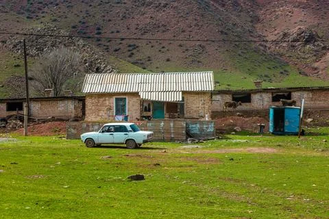 Old white car in front of rustic farm house in Kyrgyzstan Stockfoto's