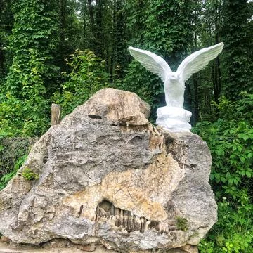 Old white eagle statue on stone in forest Stock Photos