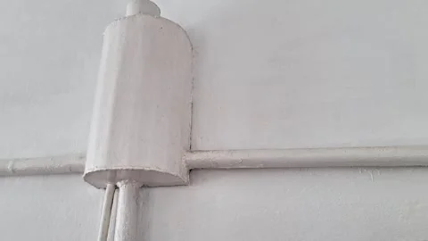 Old White Heating Expansion Tank and Pipes Mounted on an Indoor Wall Stock Footage 345475029