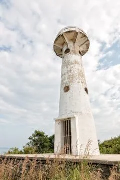 Old white lighthouse with clouds in the background Stock Photos