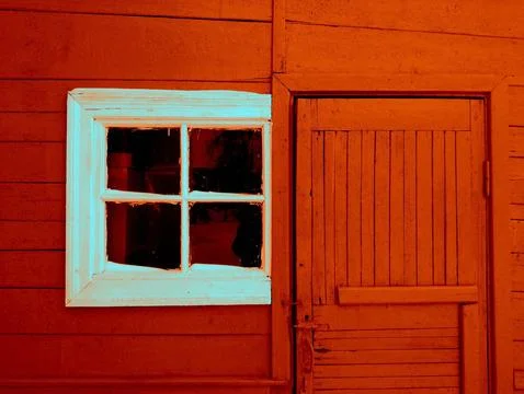 An old white-painted window on a red house. Stock Photos