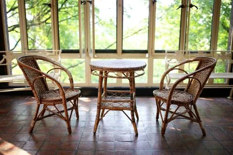 Old Wicker Bistro Table and Chairs in Sun Room Patio of Historic House Stock Photos