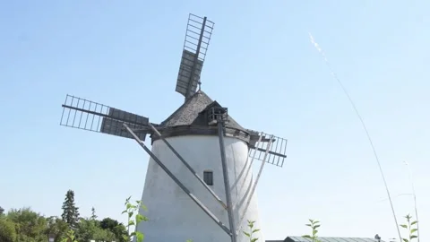 Old windmill, blades spinning in the wind, rural landscape, blue sky, Europe, Au Stock Footage 249961088