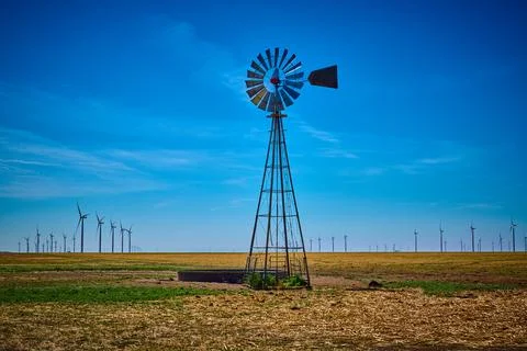 Old windmill in a field of modern wind turbines west of Amarillo Texas. Stock Photos