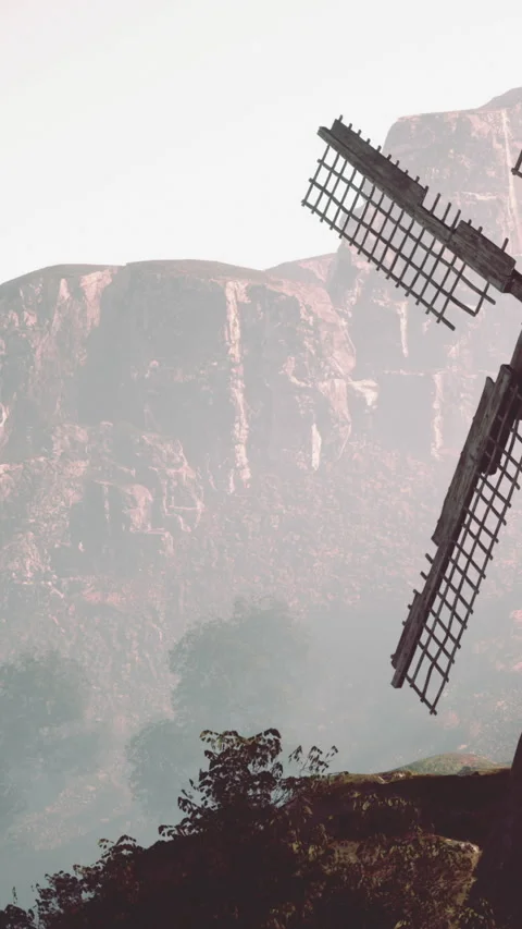 Old windmill stands near mountain in misty landscape at dawn Stock Footage 337999042