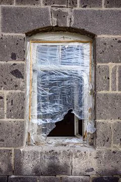 Old window frame cracked, wrapped in plastic on stone building Stock Photos