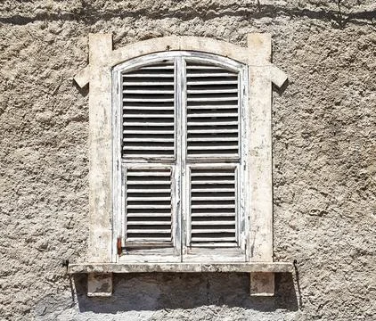 Old window isolated. White closed shutters on the background of a gray ragged Stock Photos