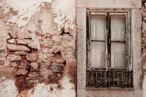 Old window in very old wall with stonework and broken plaster in Tavira, Po.. Stock Photos