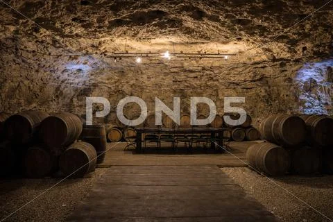 An old wine cellar with oak barrels full of red wine Stock Photos
