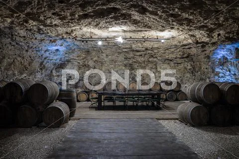 An old wine cellar with oak barrels full of red wine Stock Photos