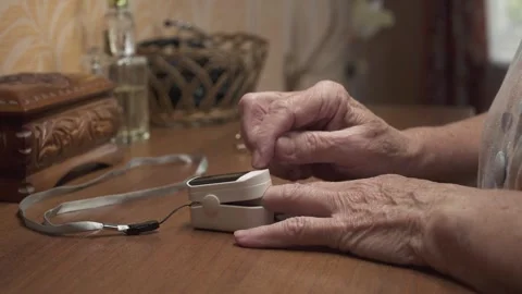 Old woman checking oxygen saturation in blood at home. Hands close-up. Stock Footage 254487802