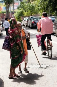 Old woman crossing road with her blind husband. Stock Photos