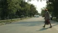 Old woman crossing street with bags, traffic rules, police car on background HD Footage