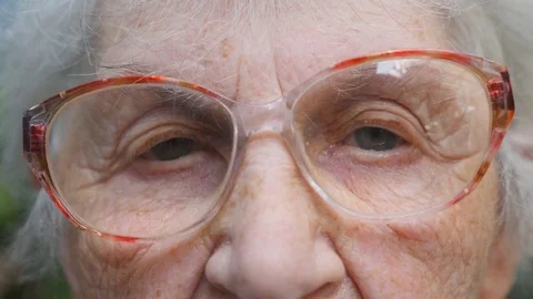 Old woman in eyeglasses looking into camera. Eyes of an elderly lady with Stock Footage