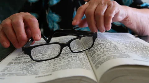 Old woman with glasses reading Bible Vídeos de archivo 64972353