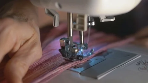 Old woman hands pushing textile through sewing machine in slow motion Stock Footage 70458802