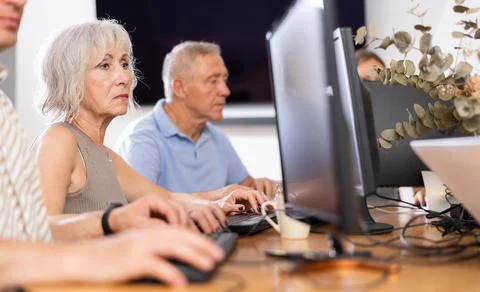 Old woman learning computer programs in training room Foto stock