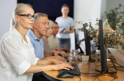 Old woman learning computer programs and teacher speaking on the background Stock Photos