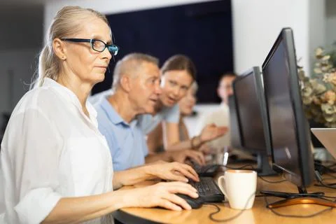 Old woman learning computer programs in training room Fotos de archivo